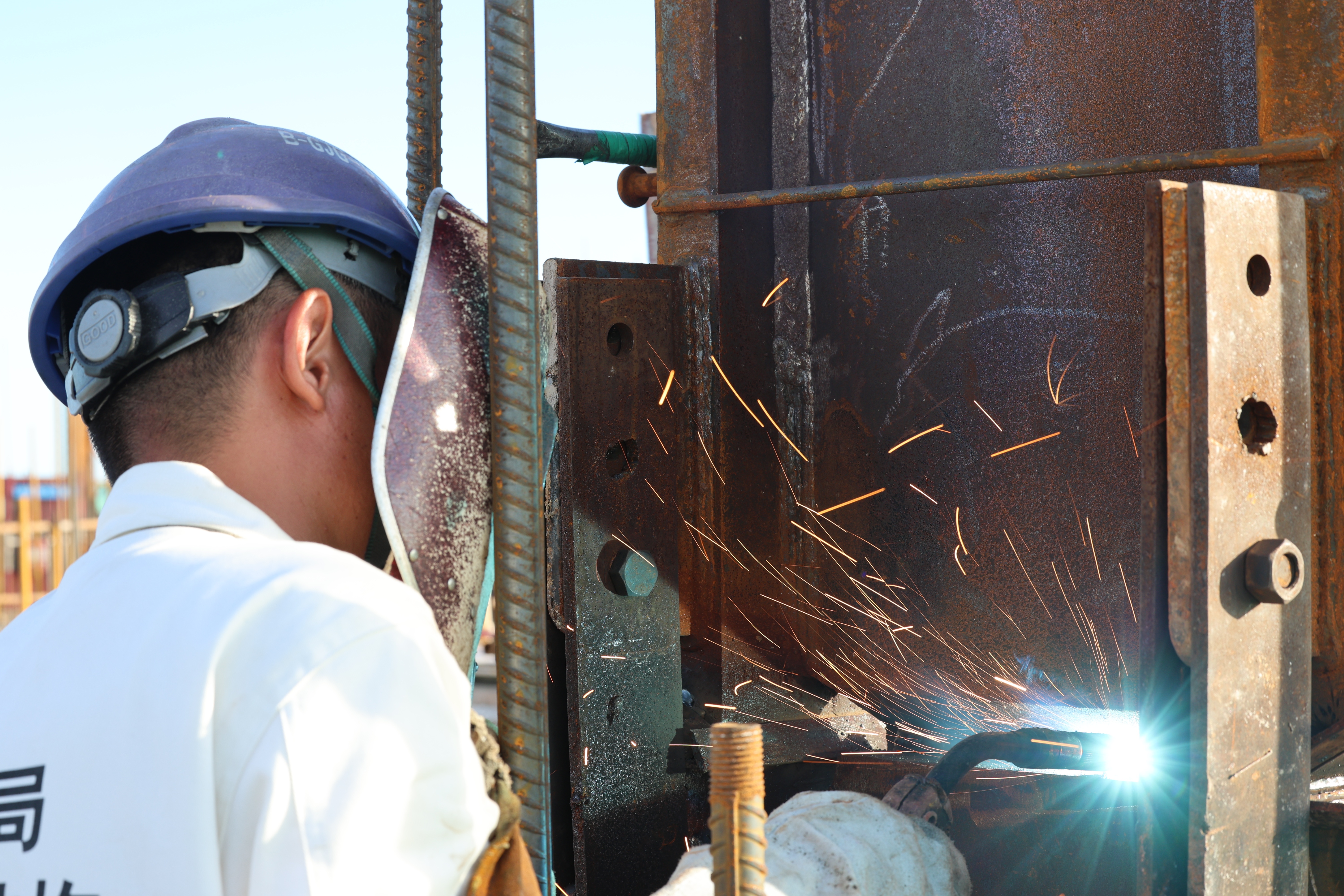 焊工正焊接着钢结构，烈日下火星四溅。