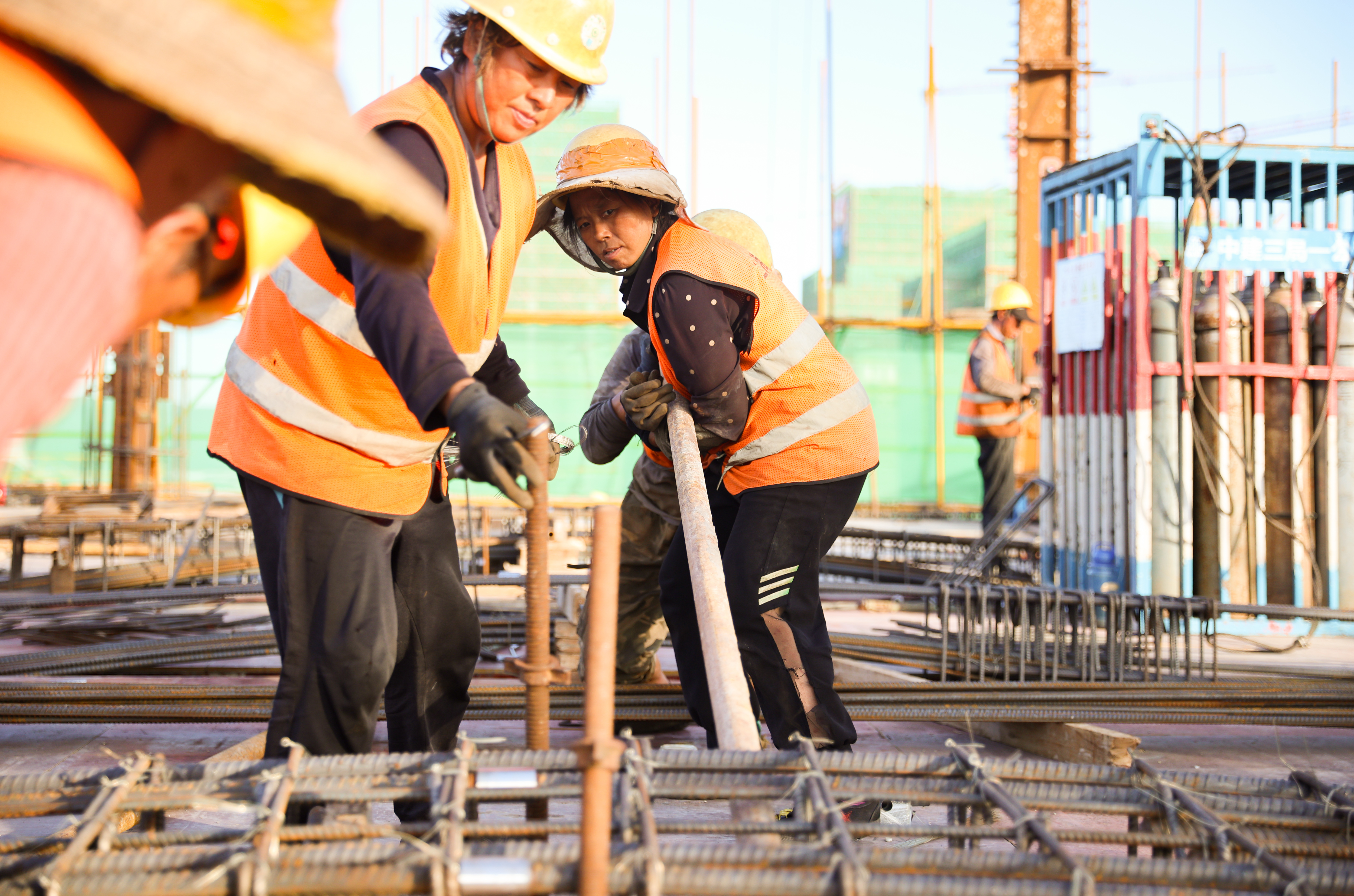 几名工人合力撬动数百斤重的钢筋。