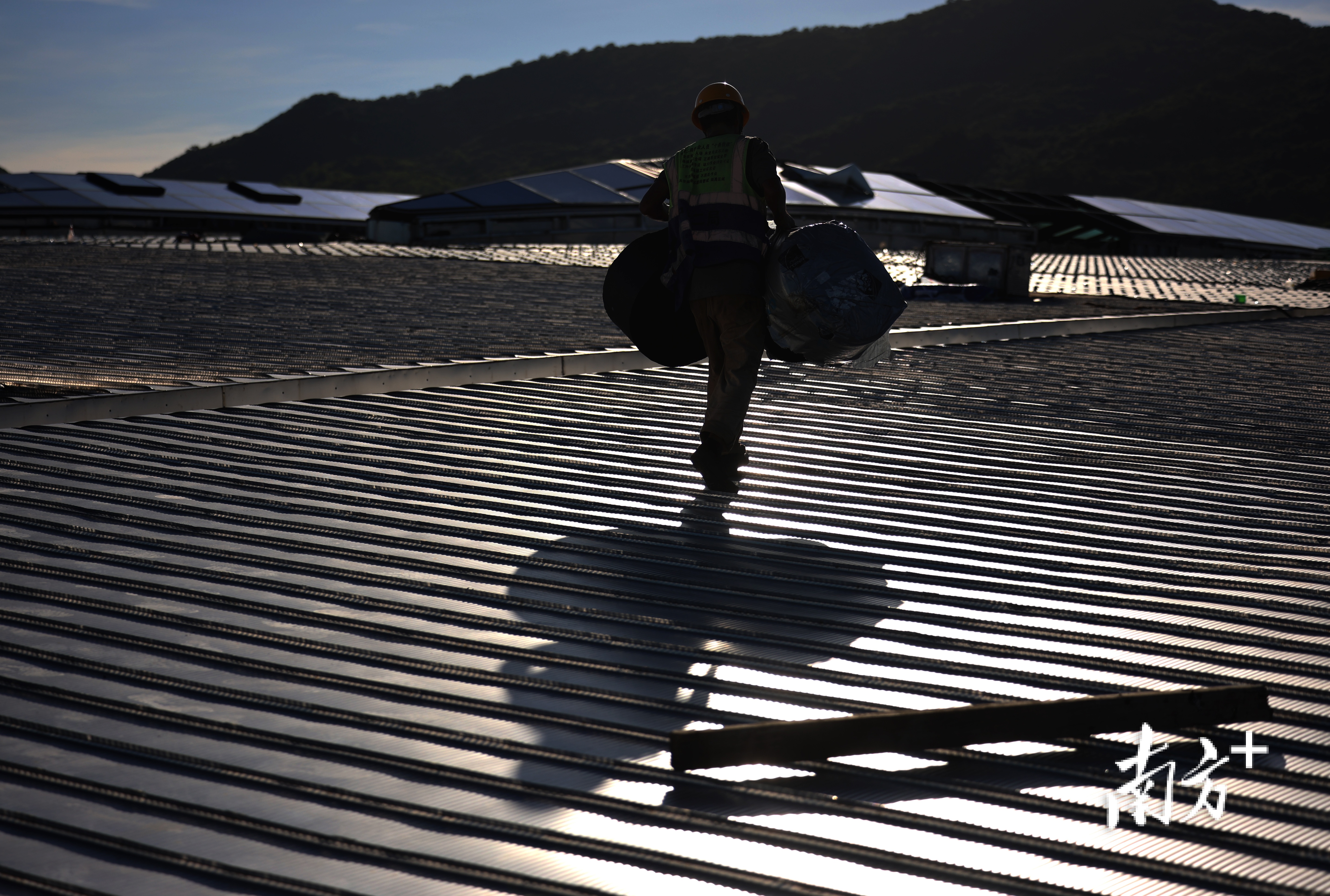 傍晚,工人们抱着建筑材料在屋面上行走。 傍晚,工人们抱着建筑材料在屋面上行走。