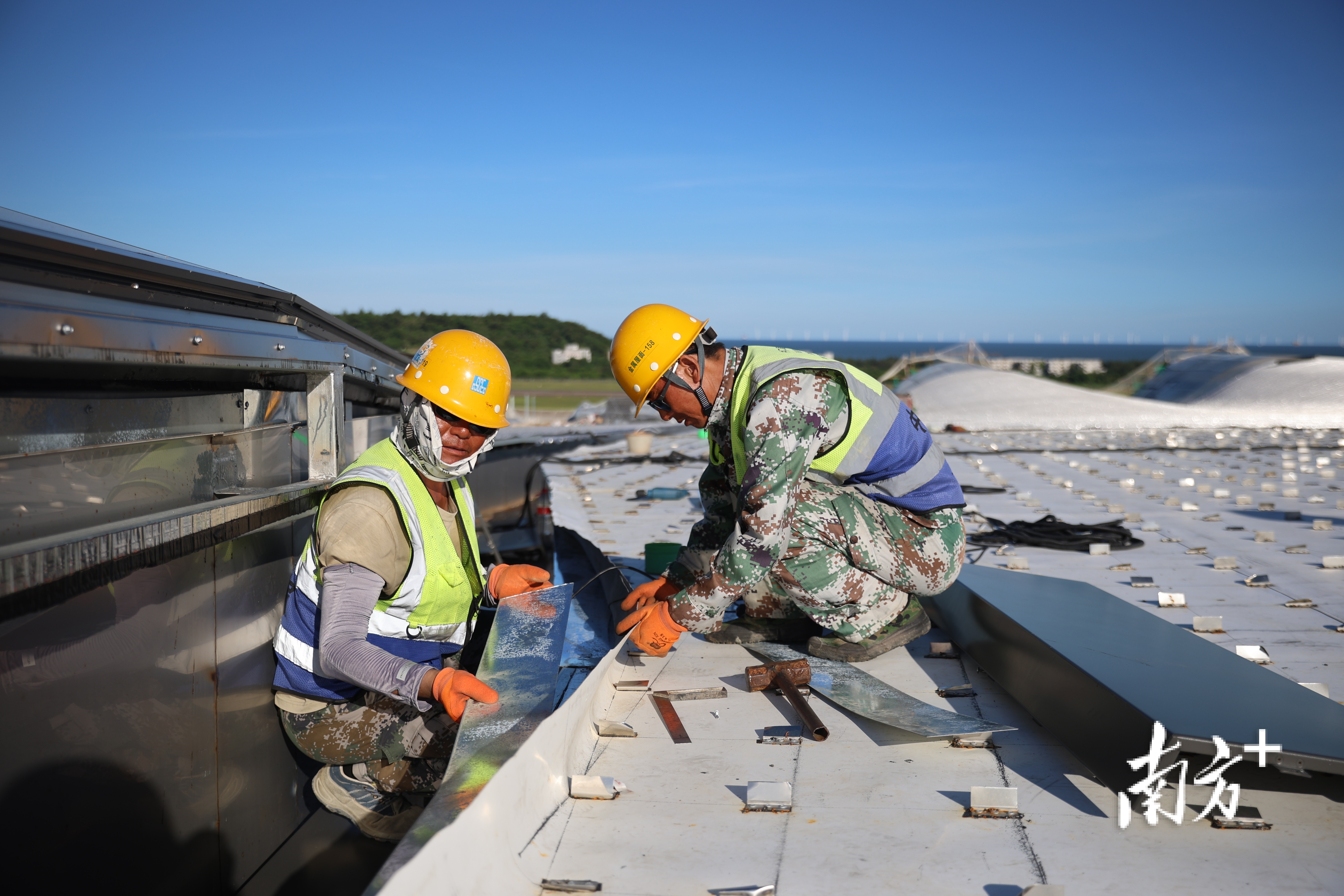 两名工人在合力铺设防水材料。 两名工人在合力铺设防水材料。