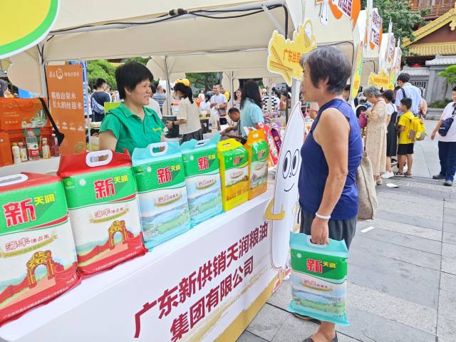 在广东新供销天润粮油集团有限公司展位前，市民周阿姨正购买汕尾丝苗米。