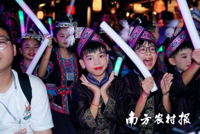  盛装参加村晚表演的侗族小朋友，坐入观众席挥舞荧光棒，耐心等待上台表演。  南方农村报 陈静 拍摄