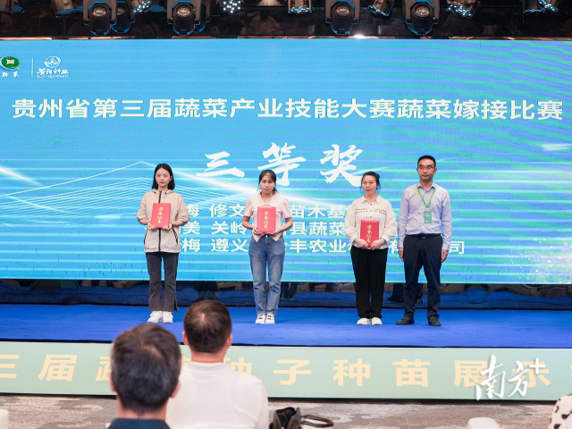 贵州省种子站站长张钟亿为吴梅、韦朝美和周继梅颁发三等奖荣誉证书