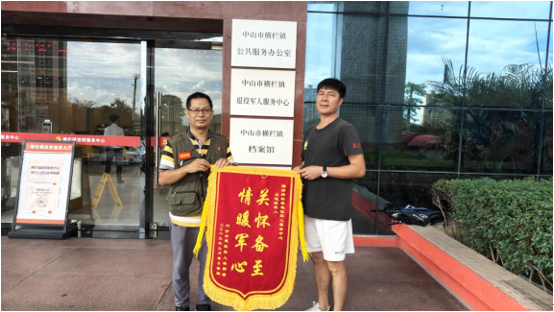 退役军人梁朝瑞委托亲属梁雄建将锦旗送到横栏镇退役军人服务中心。