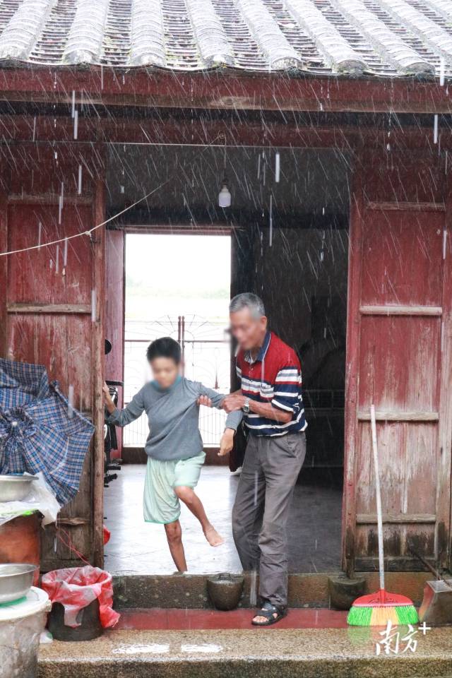 莫利红在父亲莫道侵的搀扶下跨过门槛（张璠/摄）