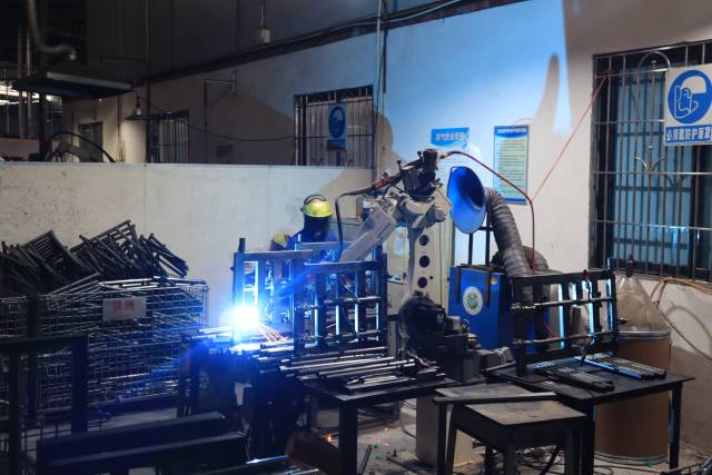 弘洲家具工厂里，一台机械臂正自动作业。