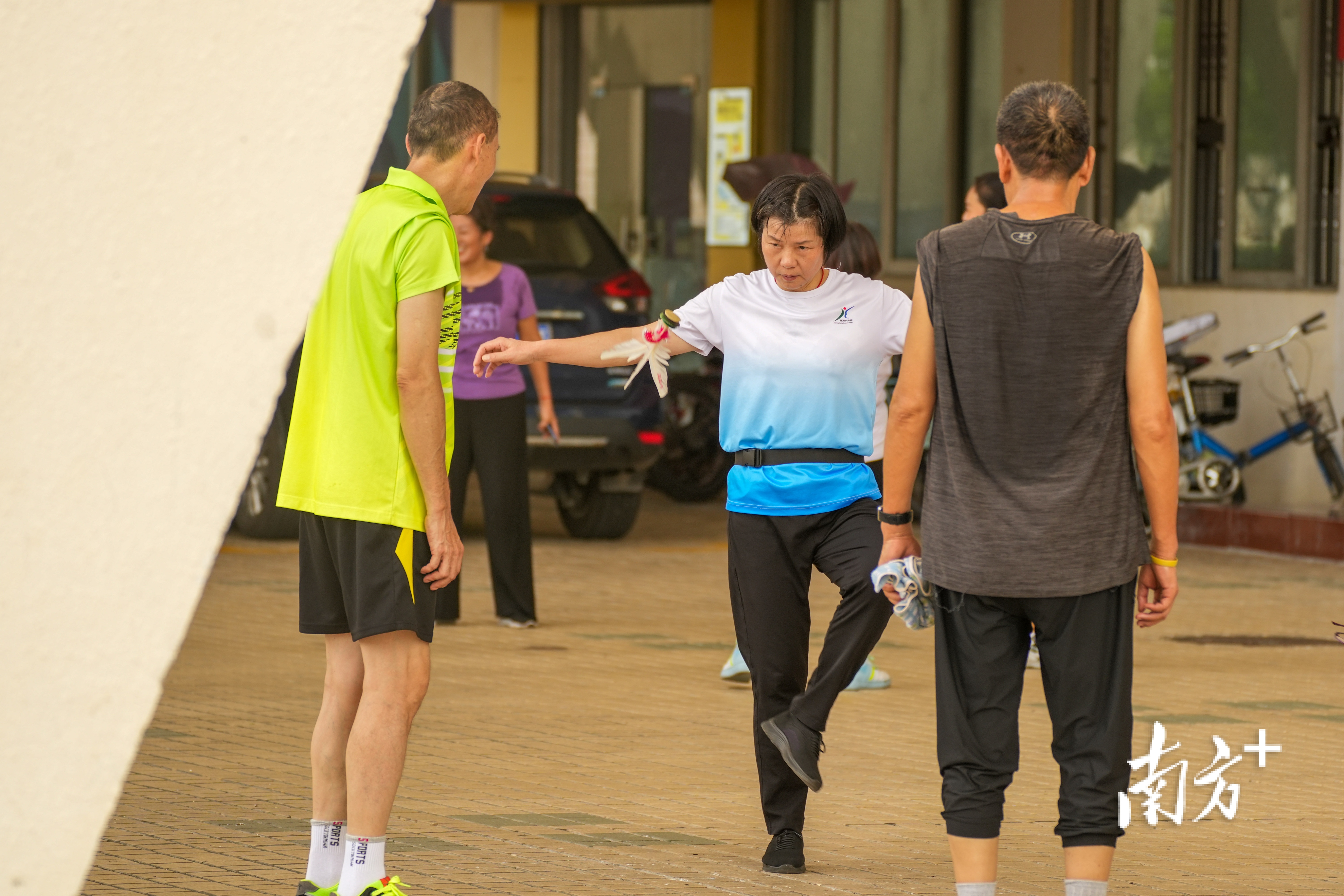 老人们围在一起踢毽子。  