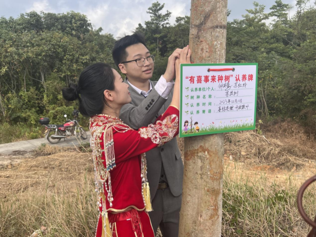 一对新人为树挂上认养牌