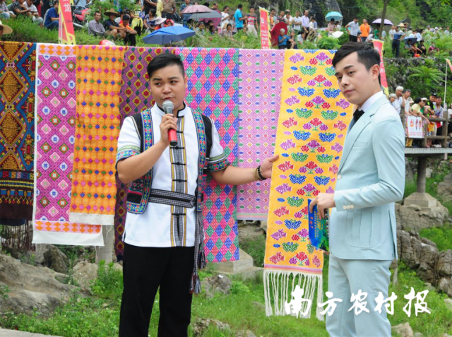 壮族小伙、壮锦技艺师蓝培文（左）向观众介绍忻城壮锦。