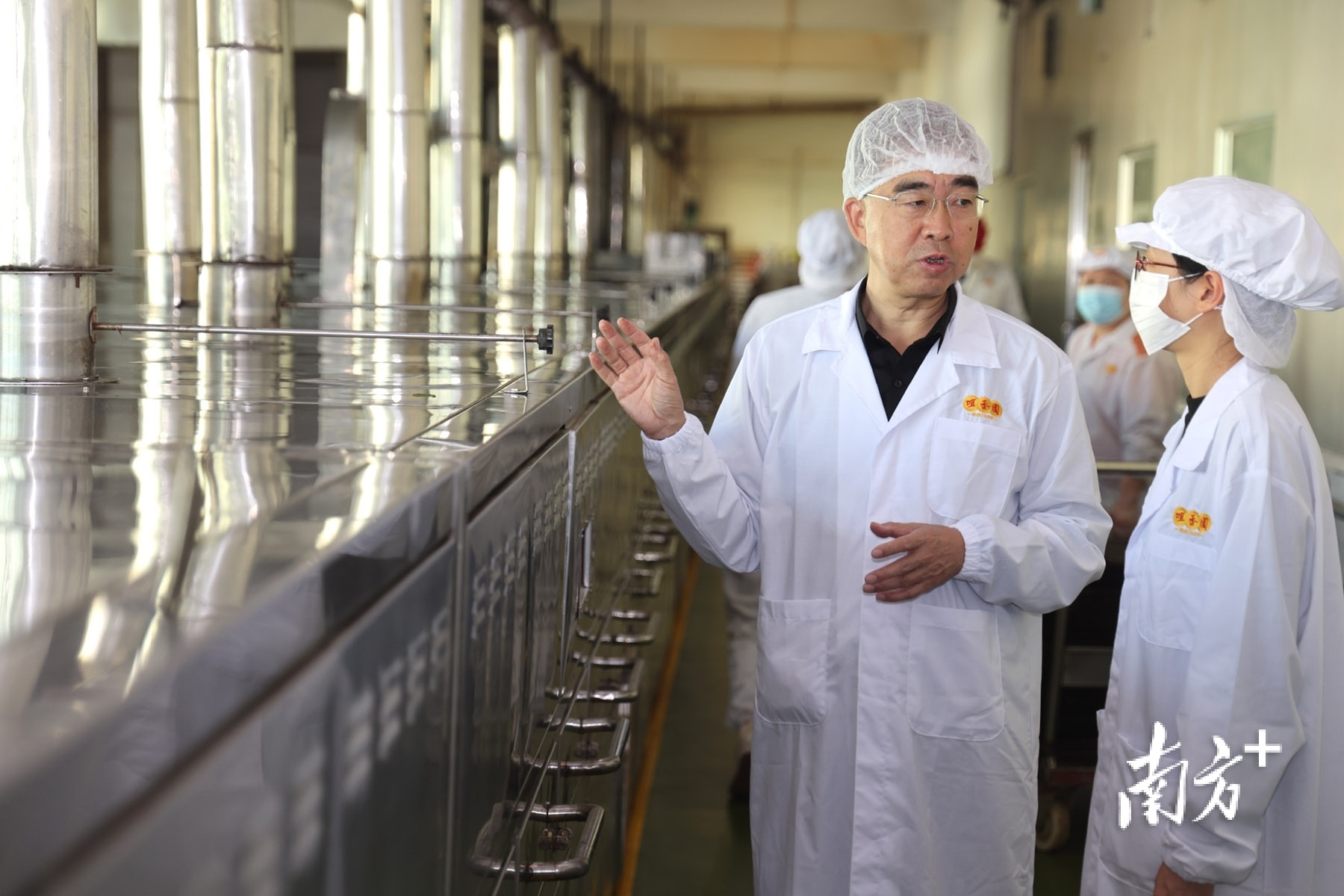 由张延杰（左）研发的杏仁饼烘烤自动化长炉，长达80米。  南方+ 叶志文 拍摄