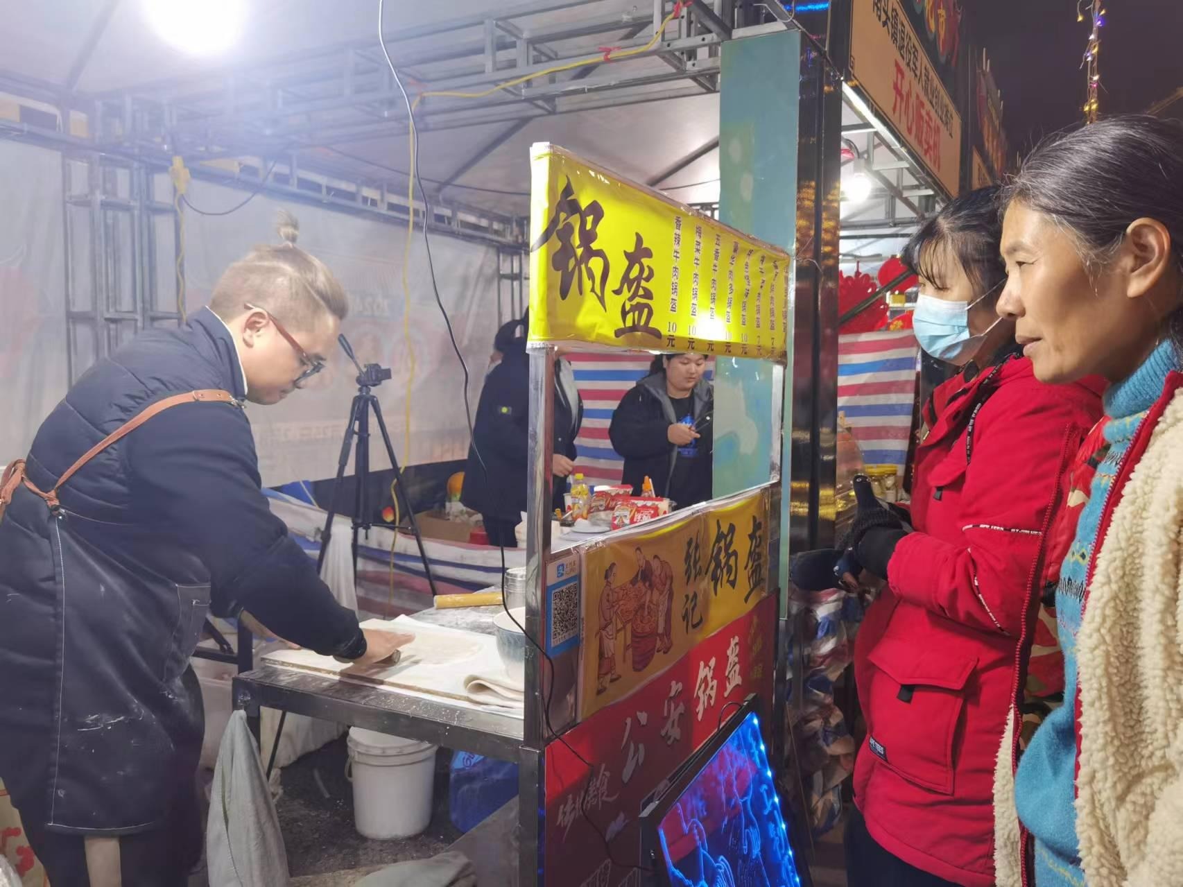 市民在南头镇退役军人就业创业摊位“老张画的饼”前等候。