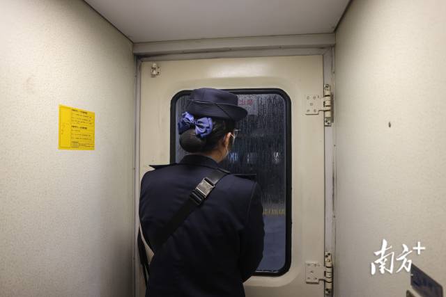 列车途经郴州站,乘务员准备开门,车门玻璃上因车厢内外温差而凝结水汽