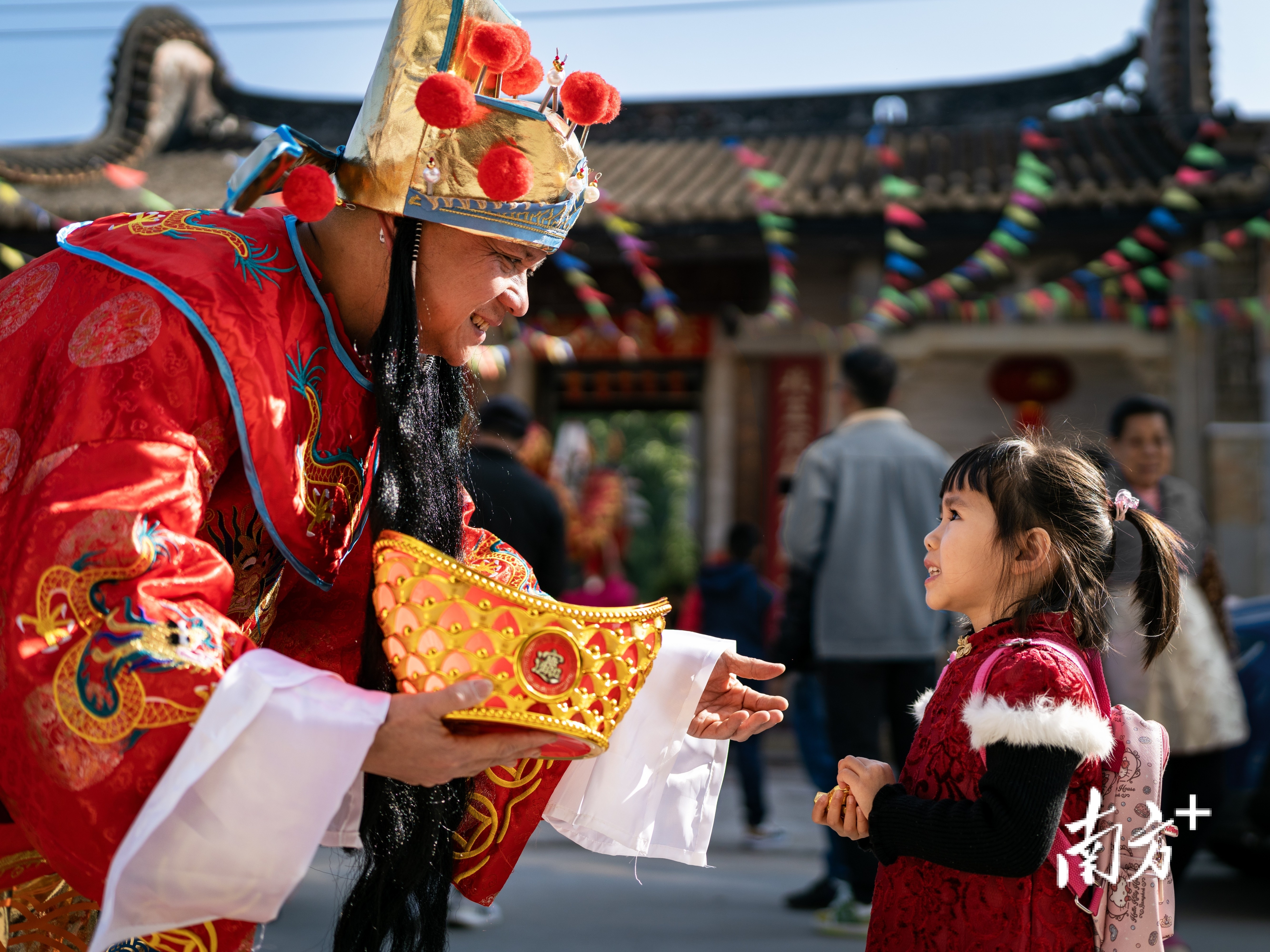2月11日,大年初二早上,中山市一古村落里,“财神爷”向一名小朋友派喜糖。卓江华 摄 2月11日,大年初二早上,中山市一古村落里,“财神爷”向一名小朋友派喜糖。卓江华 摄