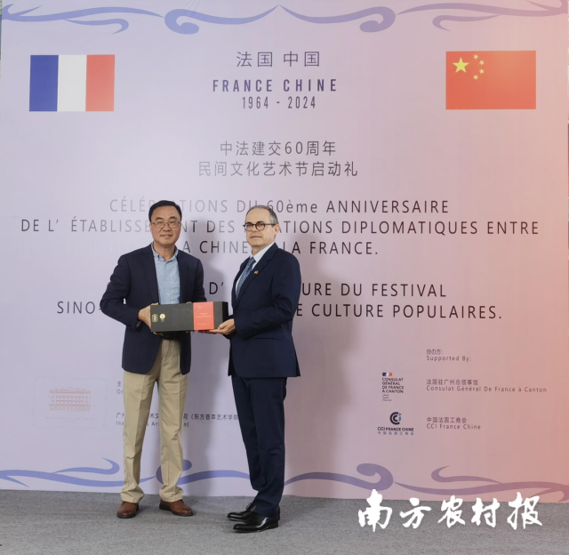 上茗轩董事长余雄辉（左）将纪念茶赠与法国驻广州总领事福希玮（右）。