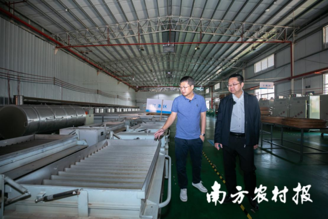 邓光（左）在茶厂进行制茶设备介绍