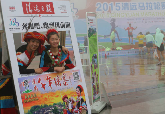 2015年3月15日，在清远马拉松赛终点两名瑶族青年在本报留影框里拍照留影。资料图
