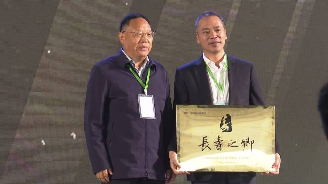 化州市委书记邓泽友接过中国长寿之乡牌匾。